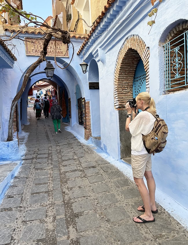 Taking a photo of a blue painted alley in Chefchaouen