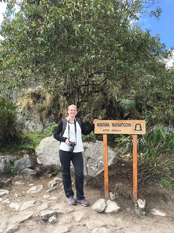 Standing next to the Huayna Picchu Mountain sign at Machu Picchu