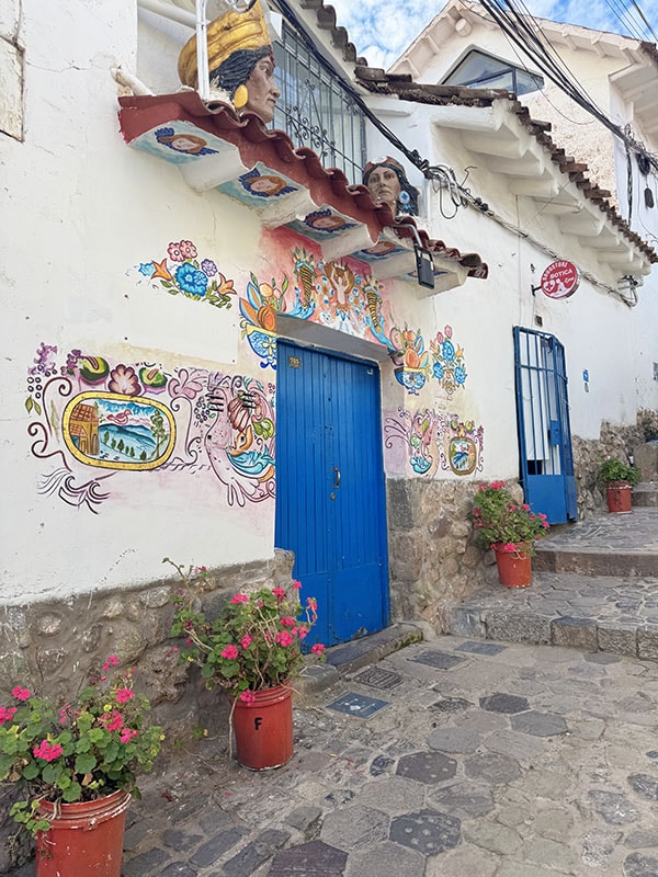 Colorful mural around a blue door in the San Blas neighborhood of Cusco Peru