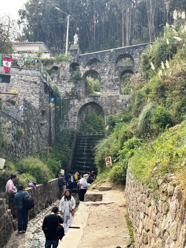 People posing in front of the Sapantiana Aqueduct in Cusco