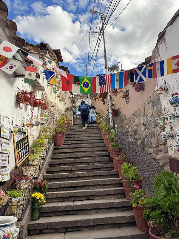 Walking up stairs in Cusco with flags of different countries draped across from one building to another
