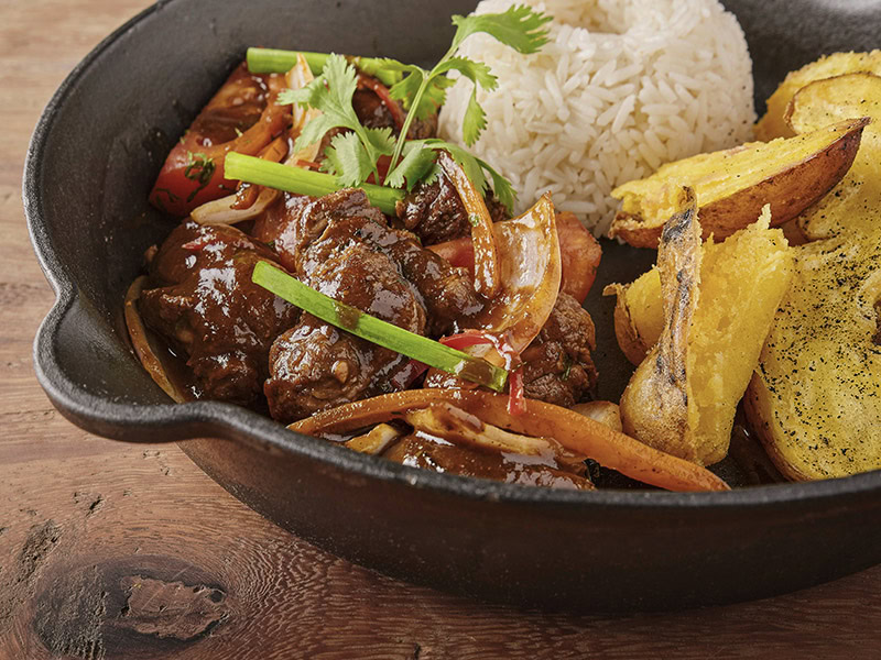 A Peruian dish: lomo saltado beef tenderloin with purple onion and yellow peppers with rice and french fries
